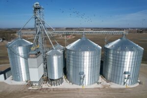aerial view of modern grain storage bins, hoppers, and handling system on an Ontario agribusiness under clear blue skies