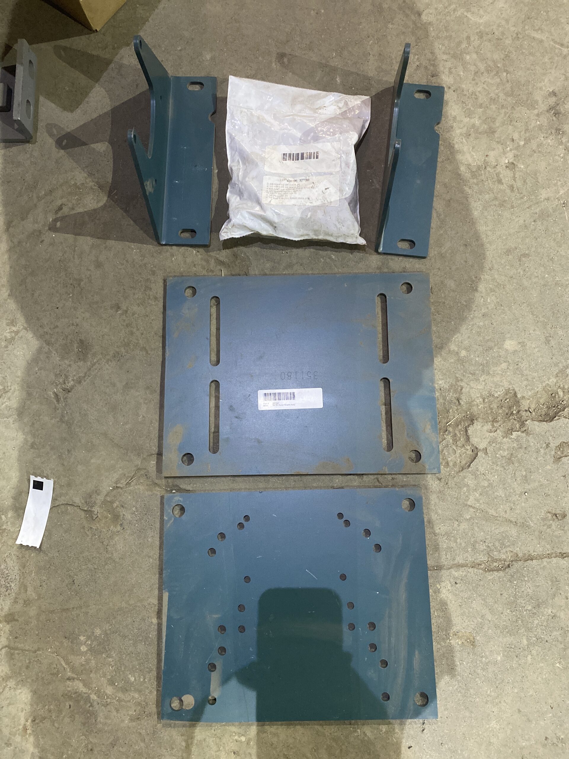 Dodge TA1M motor mount kit with steel plates, brackets, and hardware laid out on a concrete floor.