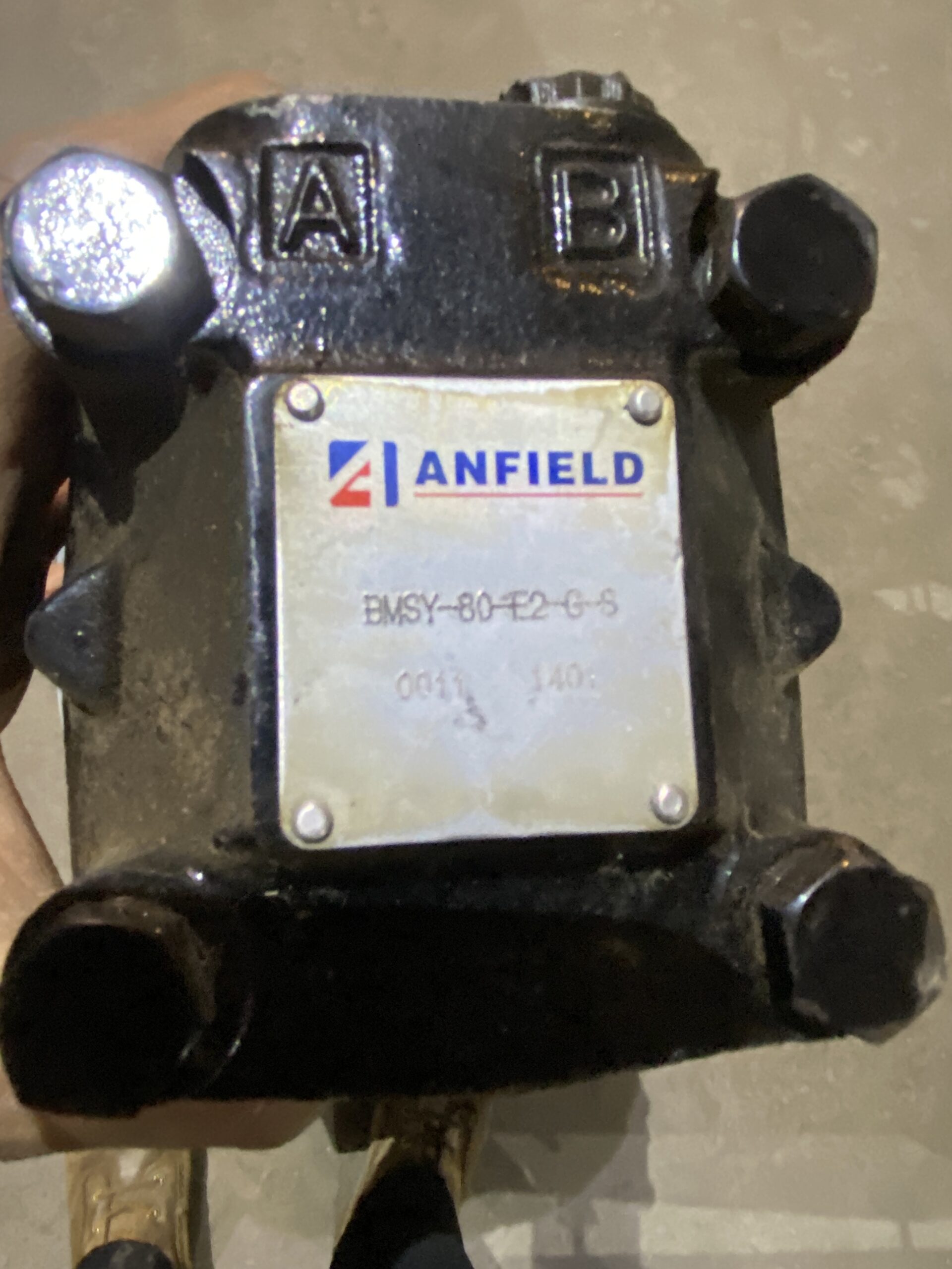 Close-up of an Anfield hydraulic motor on a used Norstar power head showing ports labeled A and B and a metal ID plate.