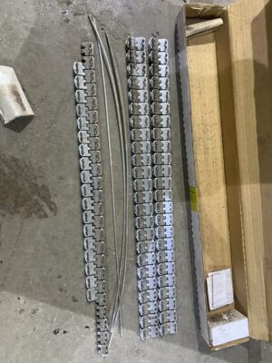 Metal Alligator splice strips and hinge pins laid out on a shop floor next to an open cardboard box.
