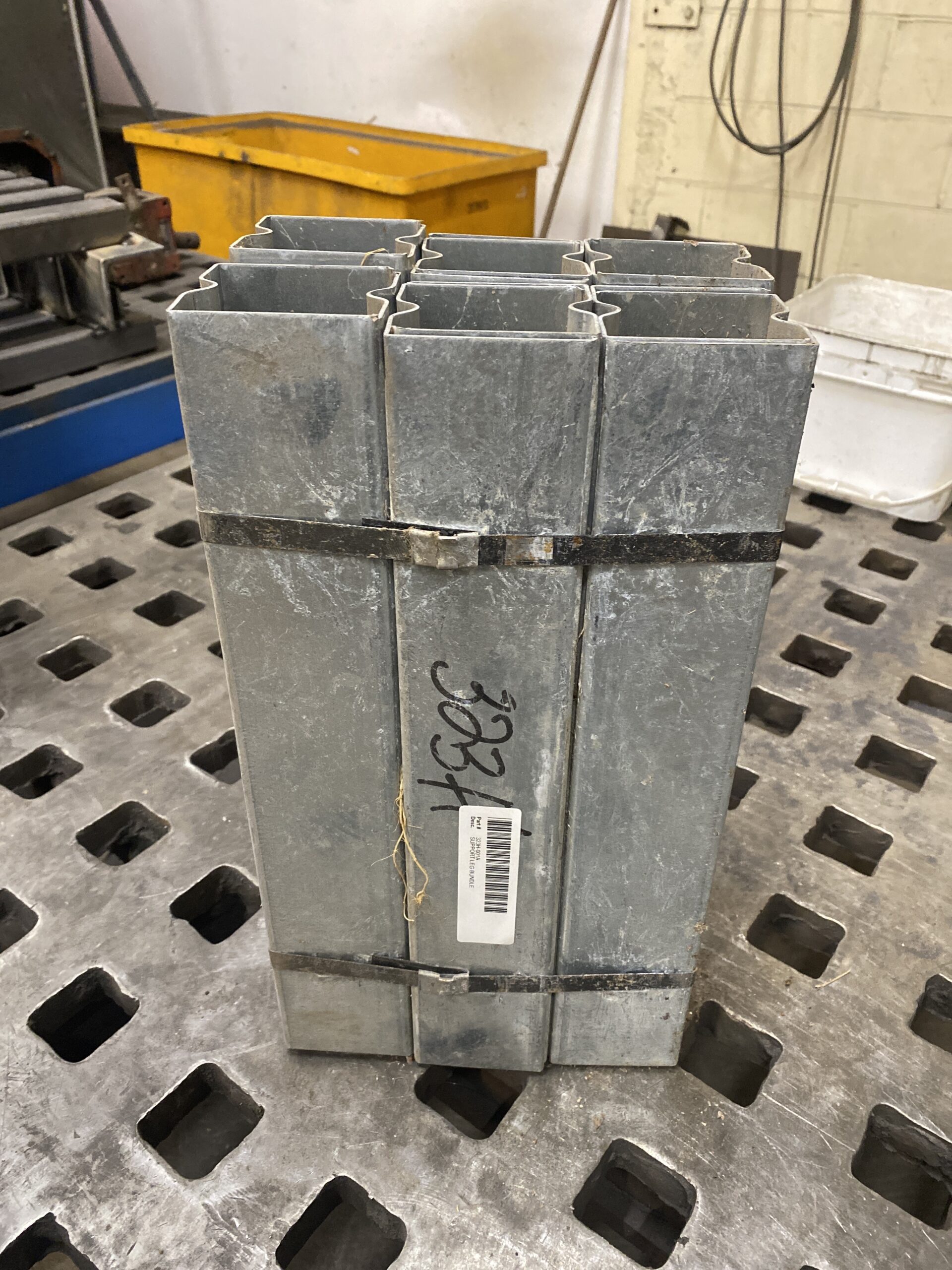 Factory bundle of twelve Shivvers galvanized grain bin floor support legs banded together on a shop table.