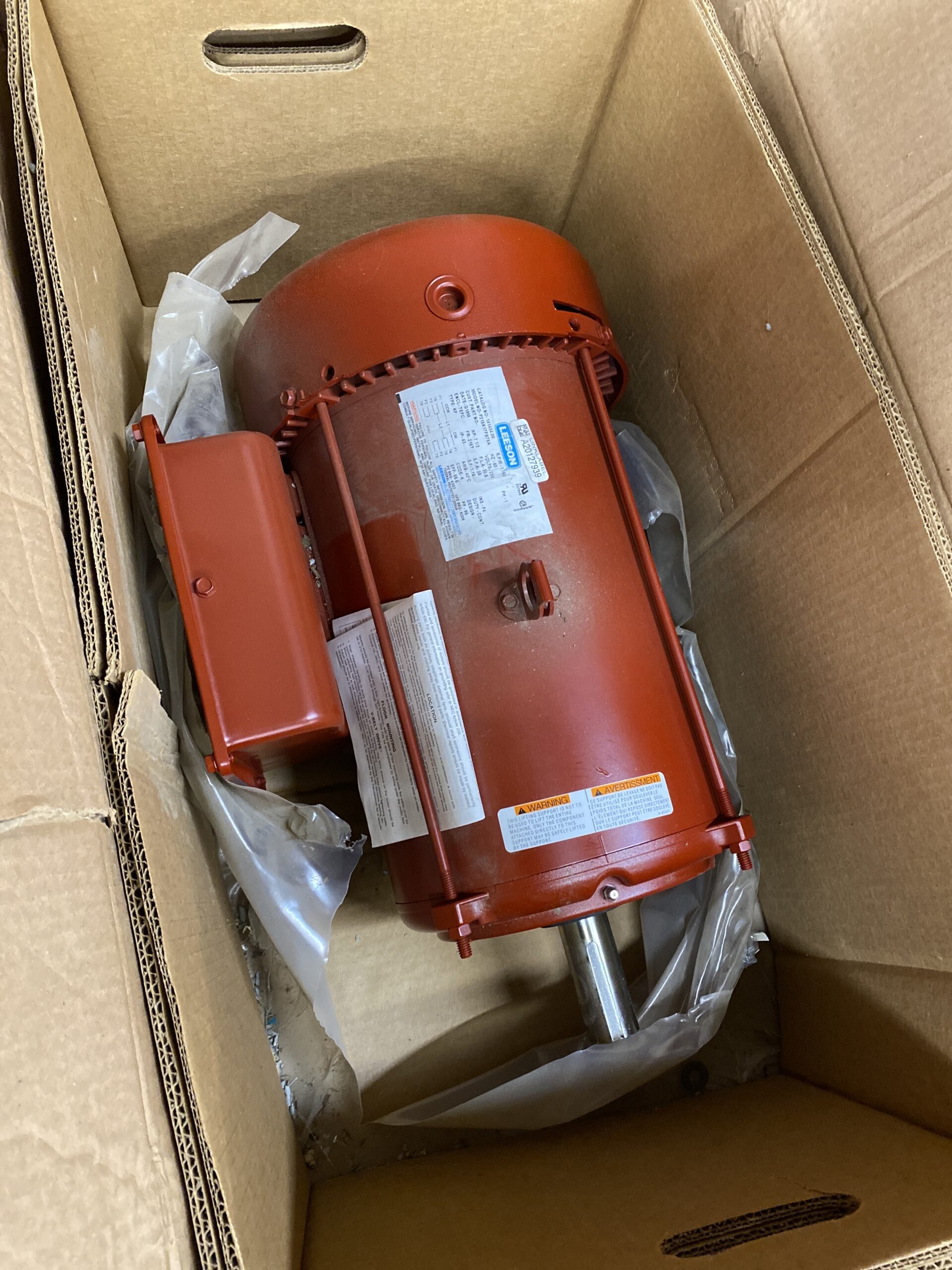 Top view of a new Leeson 7.5 HP farm duty motor inside its box with packing materials.