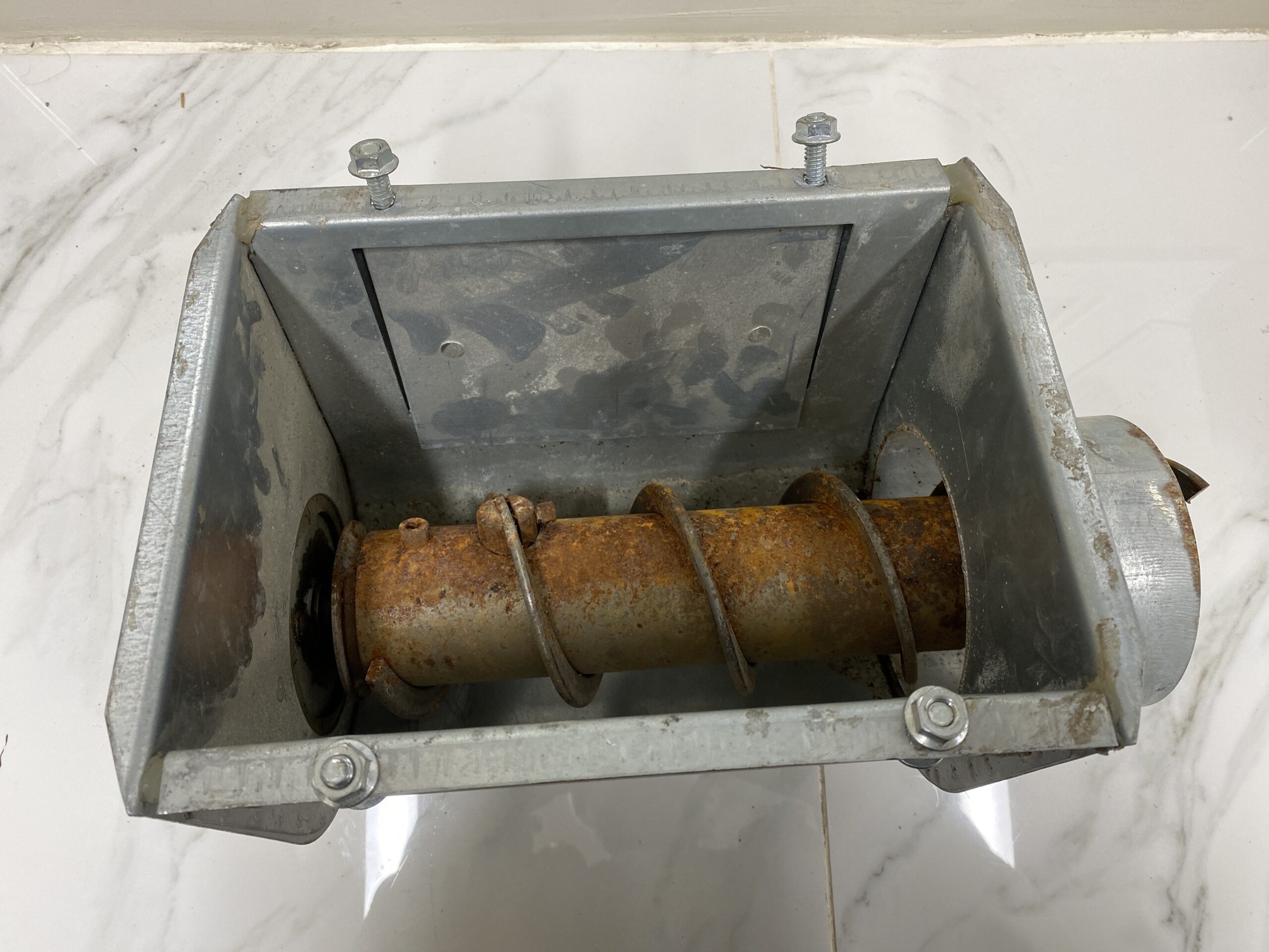 Top-down view of a RAD flex auger unloader hopper showing the internal auger flighting and rectangular galvanized housing.