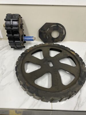 Norstar Sure‑Grip retrofit kit components including a 7‑1/4 inch toothed drive wheel, mounting plate, and drive assembly laid out on a work surface.