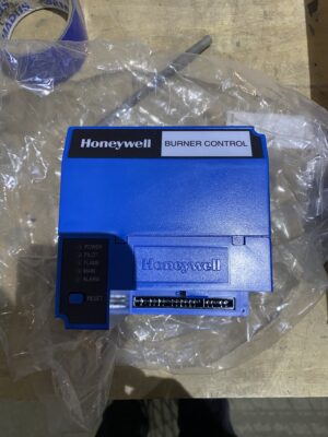 A blue Honeywell burner control module with status lights and terminal block, resting on a workbench.