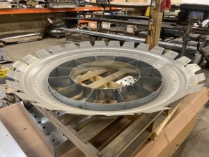 Galvanized Brock bin roof collar resting on a pallet, showing circular reinforced opening and formed mounting tabs.